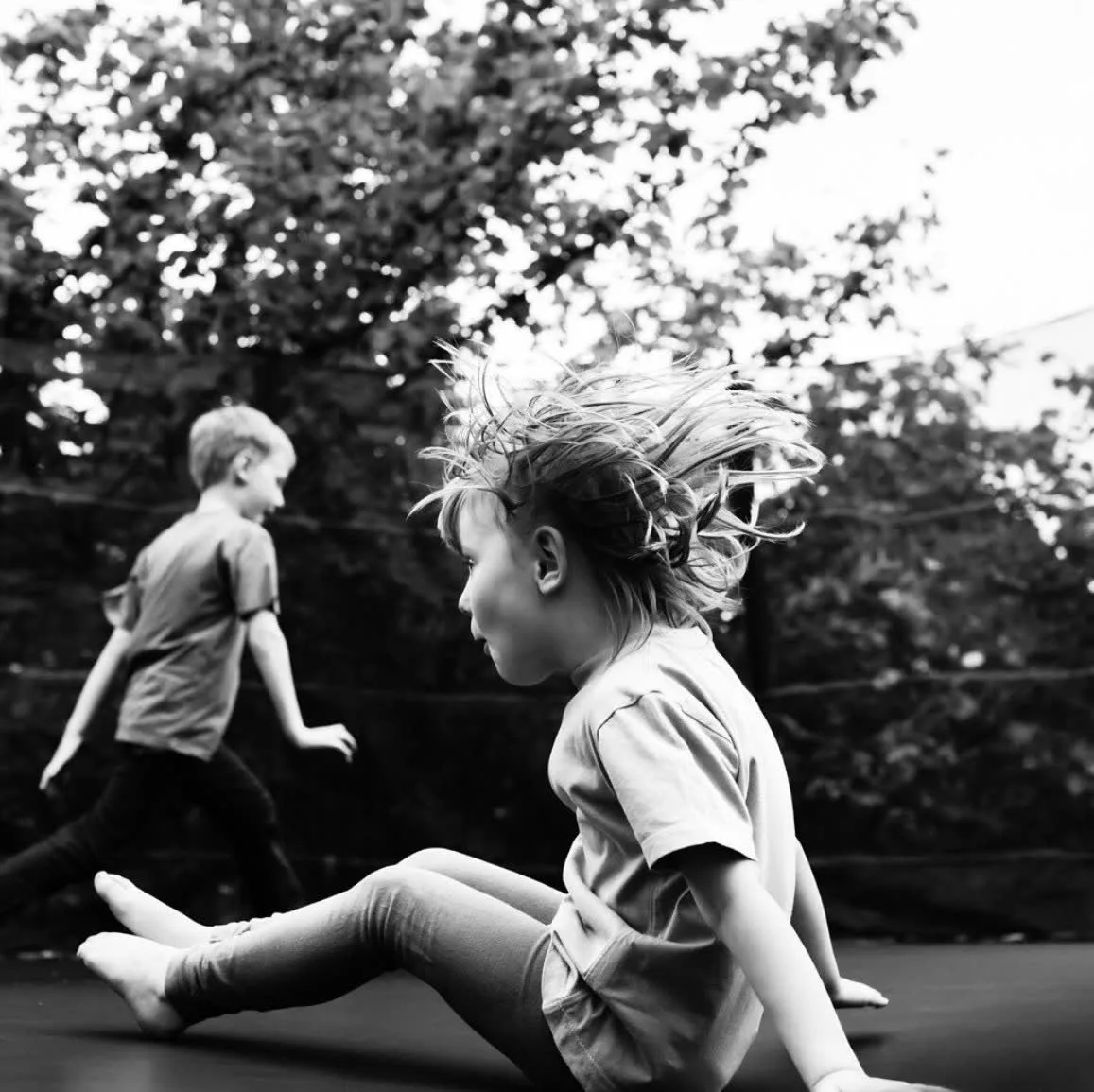 Children playing together on an in-ground Mr Trampoline in a family garden